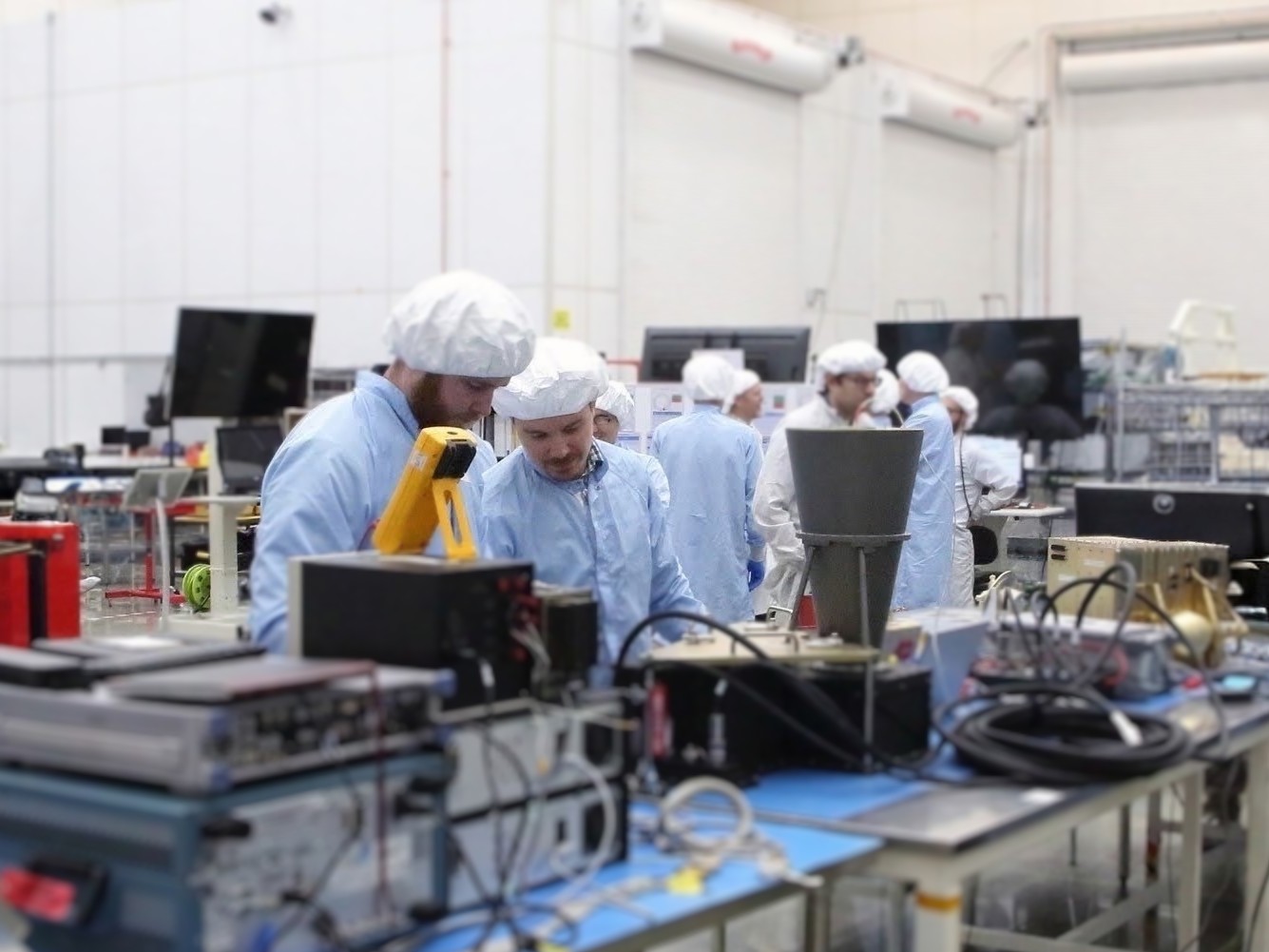 Hunter Earnest and Willie Marchetto in cleanroom garb at an integration bench in a highbay